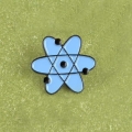 metalowa przypinka atom dekoracyjna - na tle