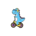 metalowa przypinka dinozaur luzak na rowerku z okularami i słuchawkami