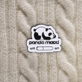 przypinka z pandą panda mood na beżowym swetrze warkocz