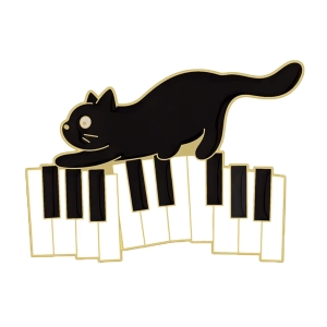 Metalowa przypinka kot na klawiaturze fortepianu