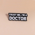 Przypinka trust me I'm a doctor - widok z bliska na beżowym tle