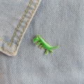 przypinka dinozaur zielony na ubraniu dżins