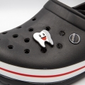 Wpinka ząb uśmiechnięty zamontowana w czarnych butach crocs